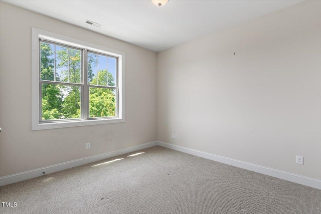 carpeted empty room featuring baseboards and visible vents