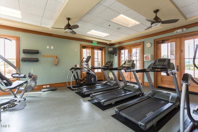 gym with a healthy amount of sunlight, a ceiling fan, and a drop ceiling