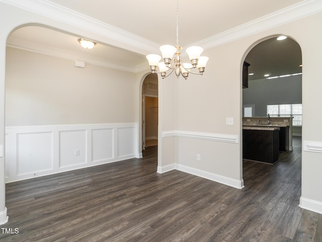 unfurnished dining area with a sink, dark wood-type flooring, arched walkways, a chandelier, and ornamental molding