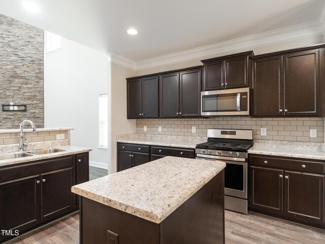 kitchen featuring a sink, dark brown cabinetry, light wood-style floors, stainless steel appliances, and tasteful backsplash