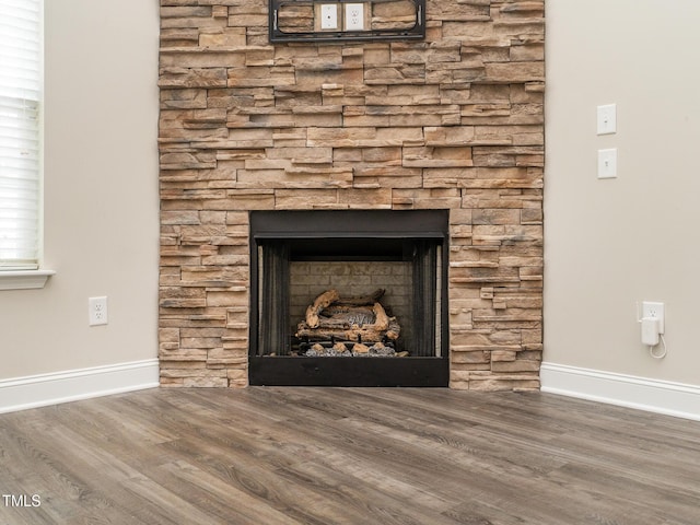 room details featuring a fireplace, baseboards, and wood finished floors
