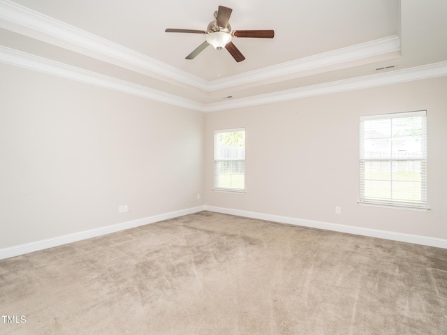 carpeted spare room featuring ornamental molding, a raised ceiling, ceiling fan, and visible vents