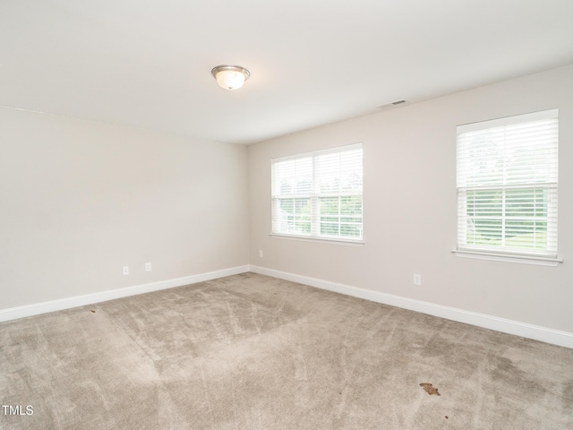 carpeted spare room with visible vents and baseboards