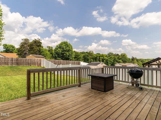 wooden deck featuring area for grilling, a yard, and a fenced backyard