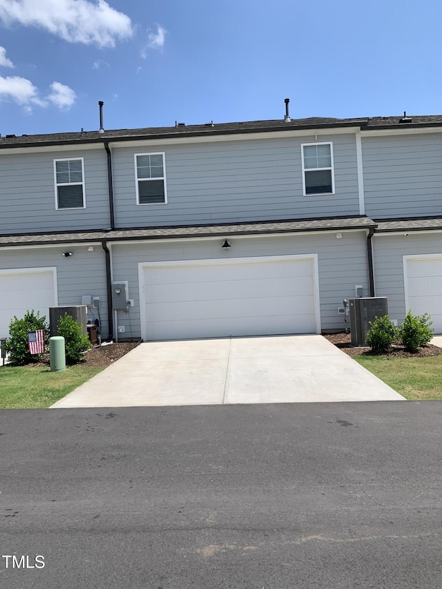 townhome / multi-family property featuring concrete driveway, a garage, and cooling unit