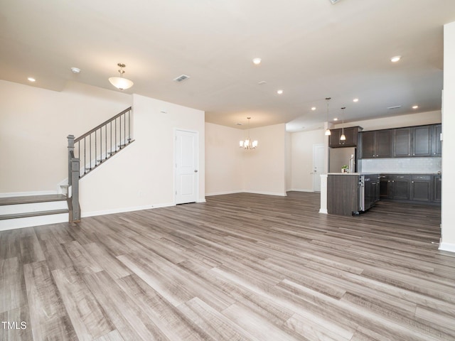 1218 S Franklin St, Wake Forest, NC 27587 - unfurnished living room with light wood finished floors, recessed lighting, a chandelier, baseboards, and stairs