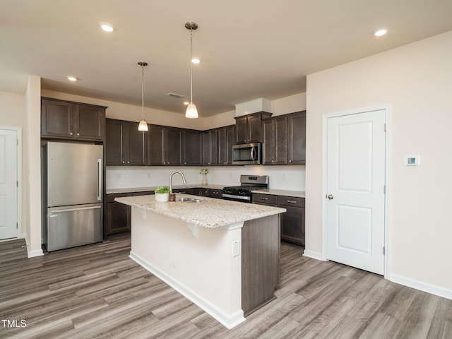 1218 S Franklin St, Wake Forest, NC 27587 - kitchen featuring appliances with stainless steel finishes, a sink, light wood-style flooring, dark brown cabinets, and a kitchen island with sink
