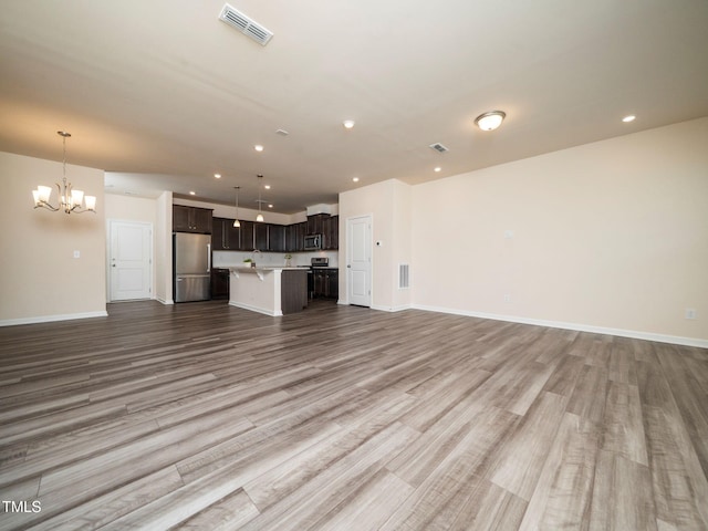 1218 S Franklin St, Wake Forest, NC 27587 - unfurnished living room featuring a chandelier, wood finished floors, a sink, recessed lighting, and baseboards