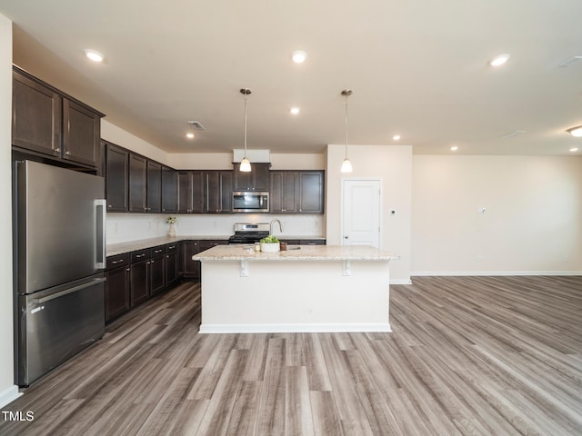 1218 S Franklin St, Wake Forest, NC 27587 - kitchen featuring stainless steel appliances, light wood-type flooring, dark brown cabinetry, an island with sink, and recessed lighting