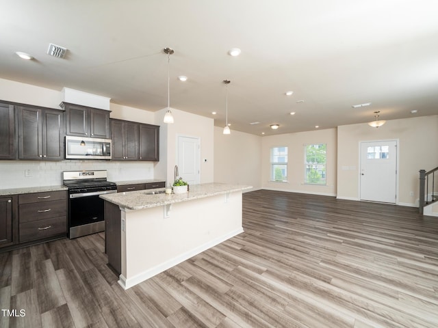 1218 S Franklin St, Wake Forest, NC 27587 - kitchen with stainless steel appliances, a sink, wood finished floors, a kitchen island with sink, and tasteful backsplash