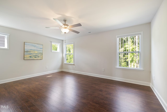 spare room with dark wood-style flooring, ceiling fan, visible vents, and baseboards