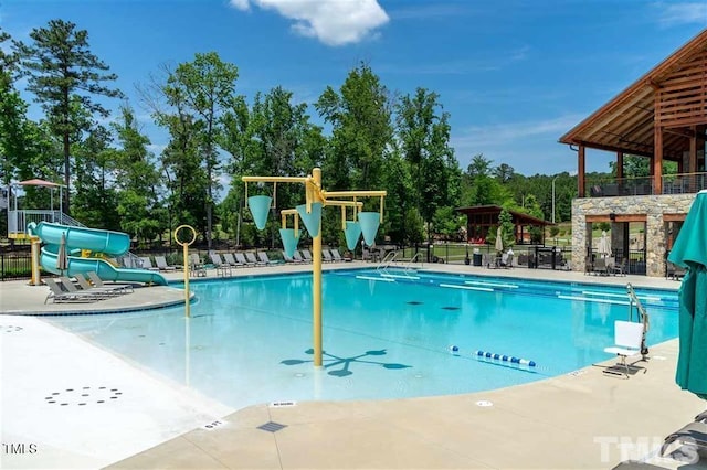 pool featuring a patio area, a water slide, and fence