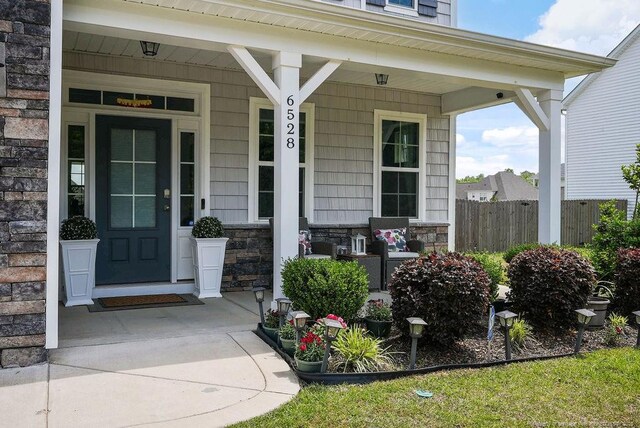 6528 Carswell Dr, Fayetteville, NC 28311 - property entrance featuring fence, covered porch, and stone siding