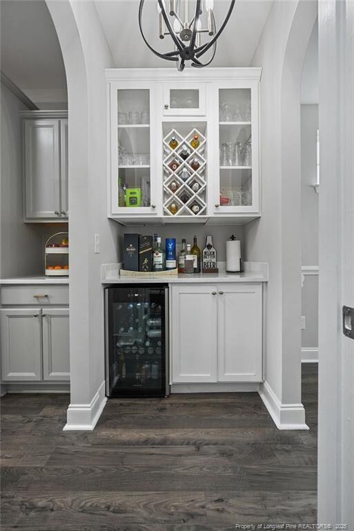 6528 Carswell Dr, Fayetteville, NC 28311 - bar with wine cooler, arched walkways, a bar, and dark wood-type flooring