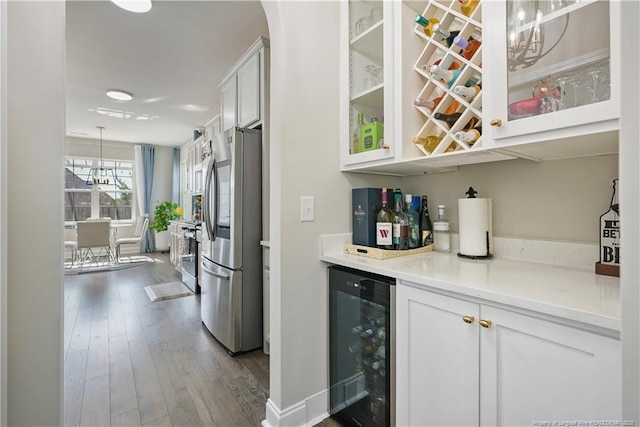 6528 Carswell Dr, Fayetteville, NC 28311 - bar with beverage cooler, dark wood finished floors, stainless steel appliances, pendant lighting, and a bar