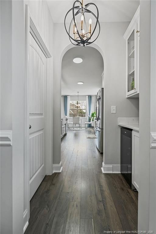 6528 Carswell Dr, Fayetteville, NC 28311 - hall featuring arched walkways, baseboards, an inviting chandelier, and dark wood finished floors
