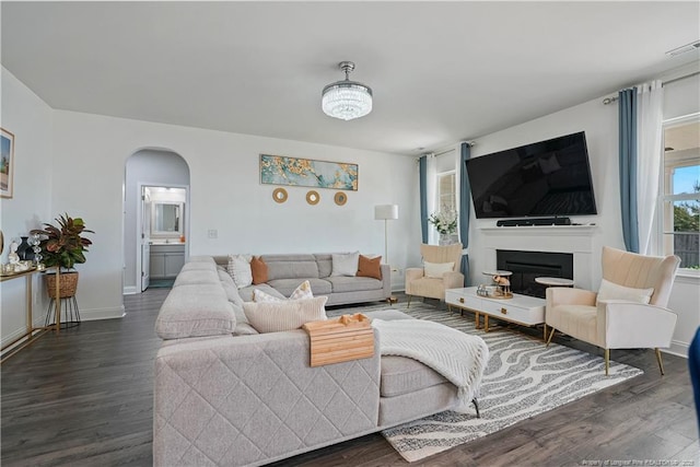 6528 Carswell Dr, Fayetteville, NC 28311 - living room with dark wood-style flooring, visible vents, arched walkways, a fireplace, and baseboards