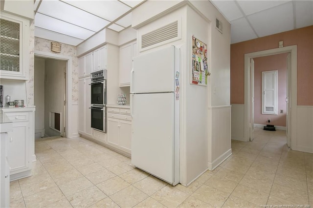 kitchen featuring visible vents, light countertops, a wainscoted wall, multiple ovens, and freestanding refrigerator