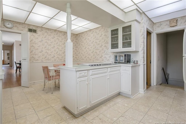 219 Devane St, Fayetteville, NC 28305 - kitchen with light countertops, a wainscoted wall, wallpapered walls, visible vents, and glass insert cabinets