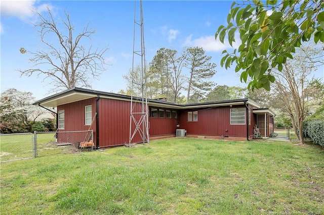 back of property featuring central AC, fence, and a yard