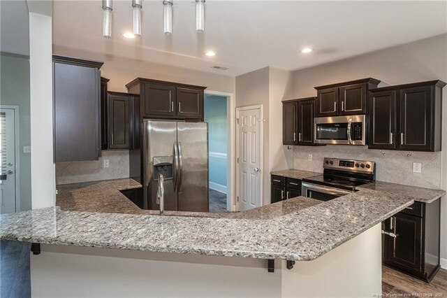 2109 Stonewash Dr, Fayetteville, NC 28306 - kitchen with decorative backsplash, a peninsula, light stone countertops, and stainless steel appliances