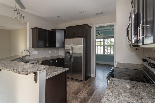 2109 Stonewash Dr, Fayetteville, NC 28306 - kitchen featuring dark wood-style flooring, light stone countertops, appliances with stainless steel finishes, a sink, and a peninsula