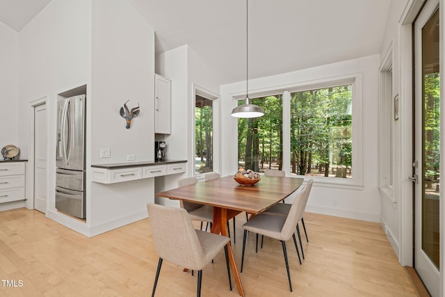 dining room with lofted ceiling, light wood finished floors, and baseboards