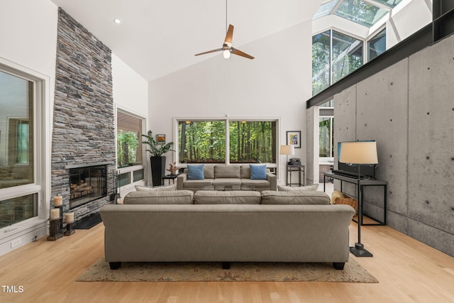 living room with high vaulted ceiling, wood finished floors, a fireplace, and ceiling fan
