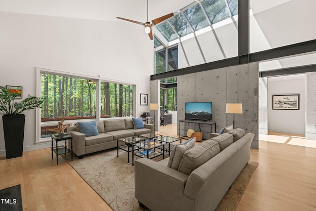 living room with a high ceiling, wood finished floors, and ceiling fan