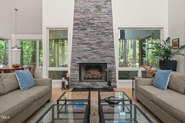 living area with a large fireplace, wood finished floors, and a towering ceiling