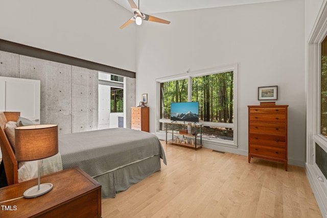 bedroom with a towering ceiling, wood finished floors, and ceiling fan