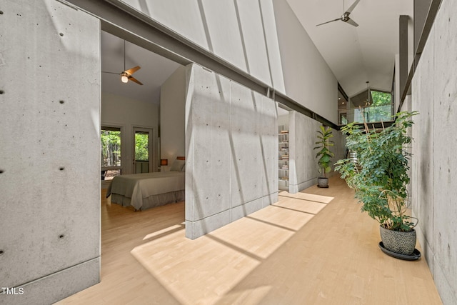 corridor featuring high vaulted ceiling, wood finished floors, and plenty of natural light