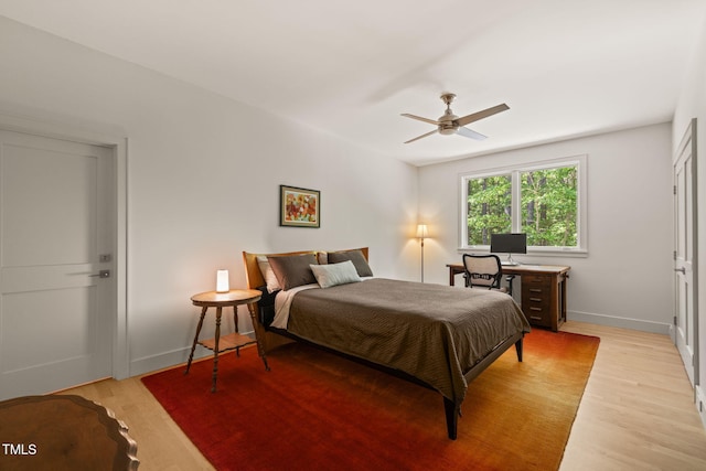 bedroom featuring light wood-type flooring, baseboards, and a ceiling fan