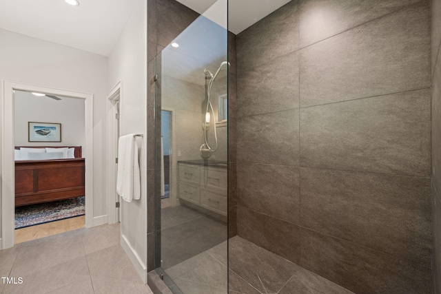 bathroom with vanity, tiled shower, tile patterned flooring, baseboards, and recessed lighting