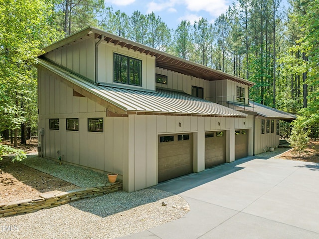 view of front of home featuring a standing seam roof, concrete driveway, board and batten siding, and metal roof