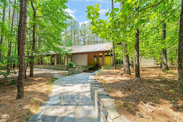 view of front of home with metal roof, stone siding, a porch, and a standing seam roof