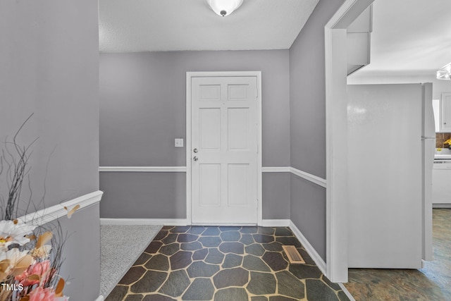 foyer with baseboards and visible vents