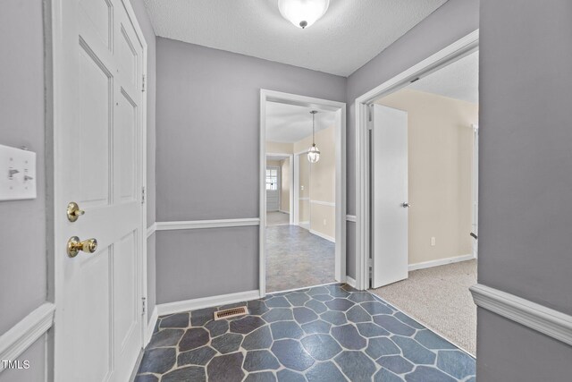 foyer featuring a textured ceiling, visible vents, and baseboards
