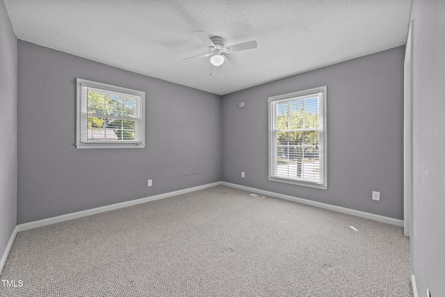 carpeted spare room featuring baseboards, a ceiling fan, and a textured ceiling