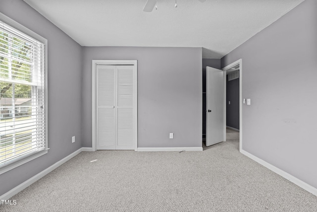 unfurnished bedroom with baseboards, a ceiling fan, a closet, and light colored carpet