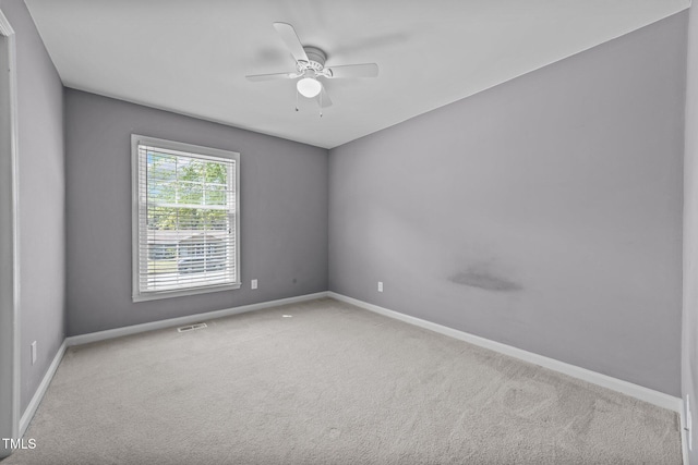 carpeted empty room featuring ceiling fan, visible vents, and baseboards