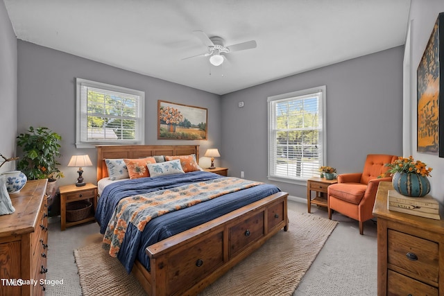 bedroom with a ceiling fan, light colored carpet, and multiple windows