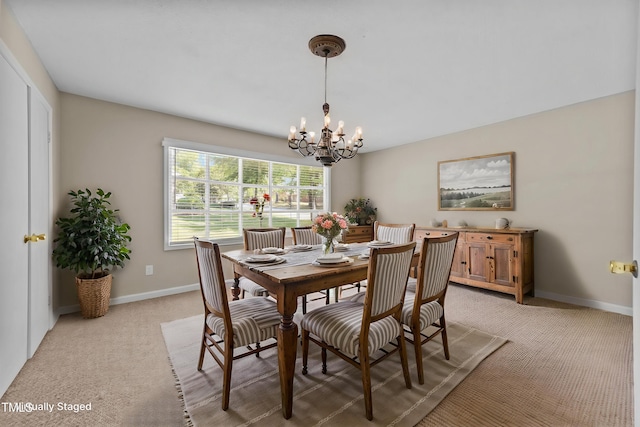 dining space with baseboards, light colored carpet, and a chandelier