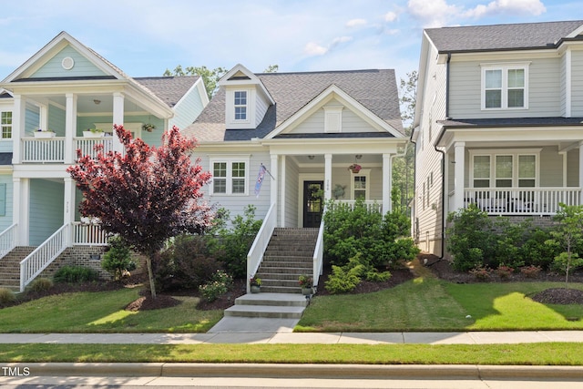 view of front of home with covered porch, stairs, and a front lawn