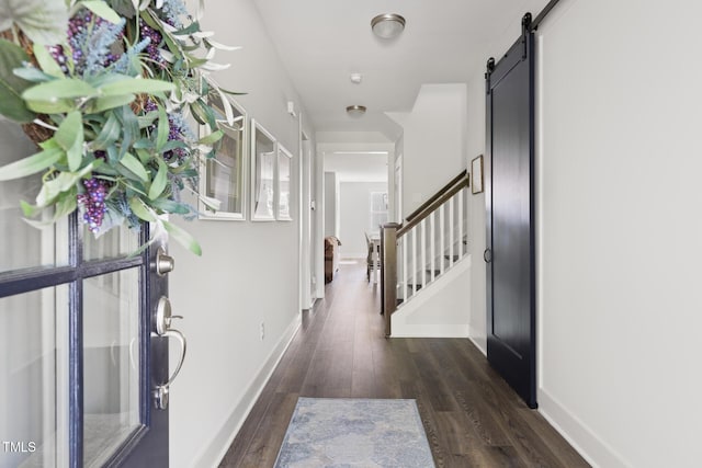 entrance foyer with baseboards, a barn door, stairs, and wood finished floors