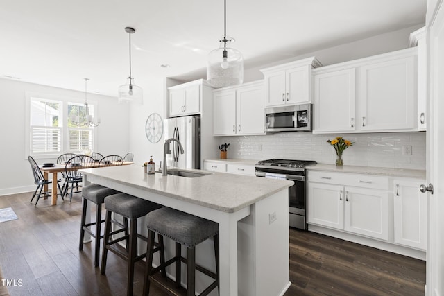 kitchen featuring backsplash, dark wood-style flooring, a kitchen bar, appliances with stainless steel finishes, and a sink