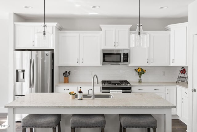 kitchen with a sink, white cabinetry, appliances with stainless steel finishes, and a breakfast bar