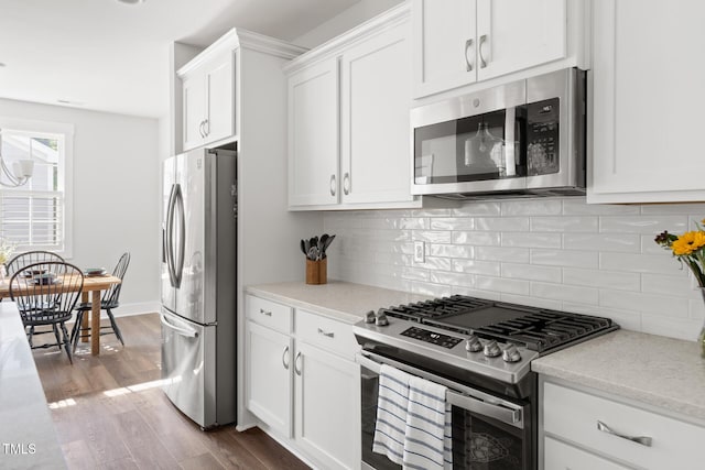 kitchen with light stone countertops, dark wood-type flooring, white cabinets, backsplash, and stainless steel appliances