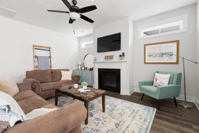 living area with baseboards, visible vents, dark wood-style floors, and a glass covered fireplace