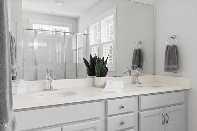 full bathroom with double vanity, a shower stall, and a sink
